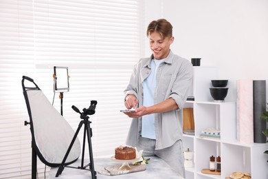 Photo of Man taking picture of chocolate cake in studio. Professional food photography