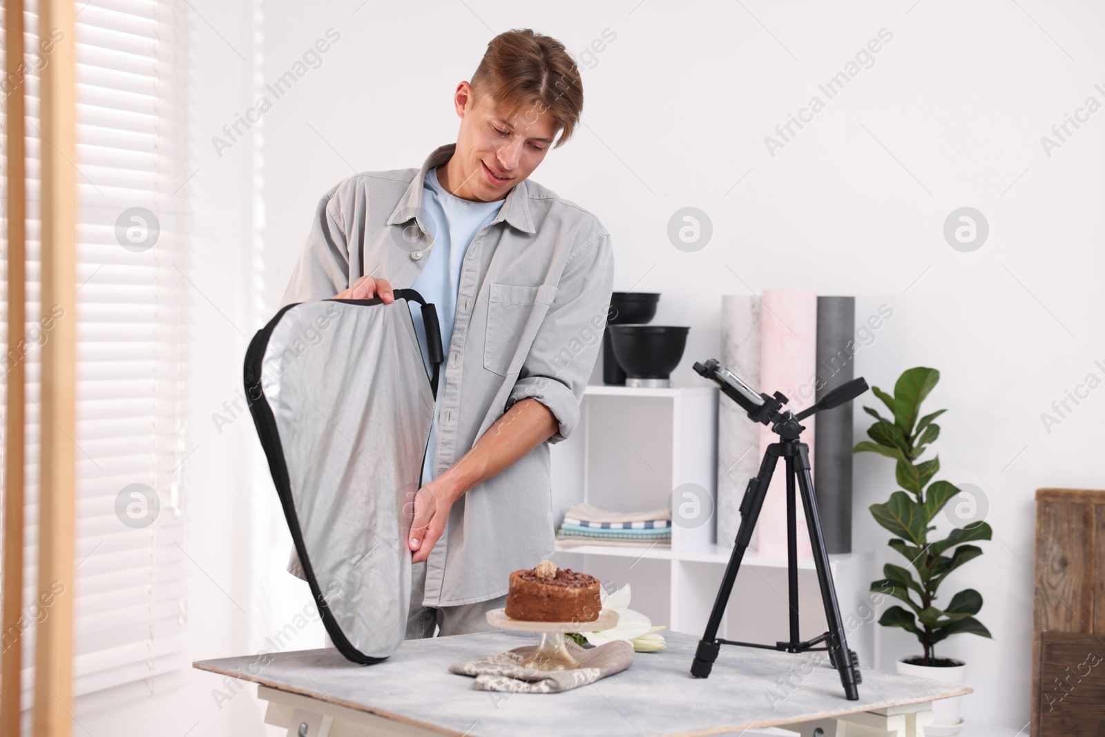Man using reflector to take picture of chocolate cake in studio. Professional food photography Photo of Man using reflector to take picture of chocolate cake in studio. Professional food photography