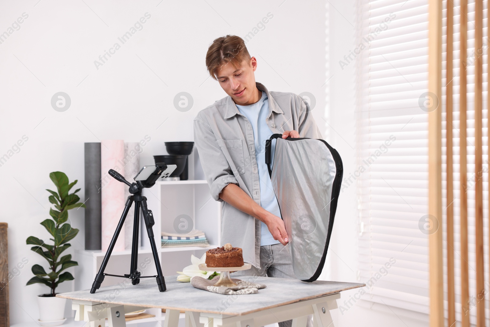 Man using reflector to take picture of chocolate cake in studio. Professional food photography Photo of Man using reflector to take picture of chocolate cake in studio. Professional food photography
