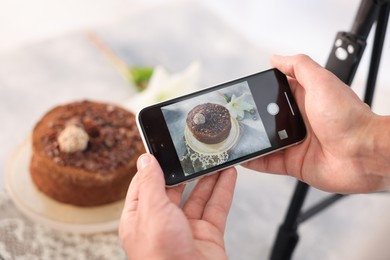 Photo of Man taking picture of chocolate cake in studio, selective focus. Professional food photography