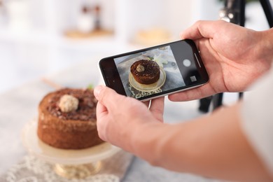 Photo of Man taking picture of chocolate cake in studio, selective focus. Professional food photography
