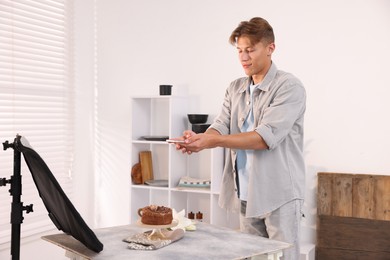 Photo of Man taking picture of chocolate cake in studio. Professional food photography