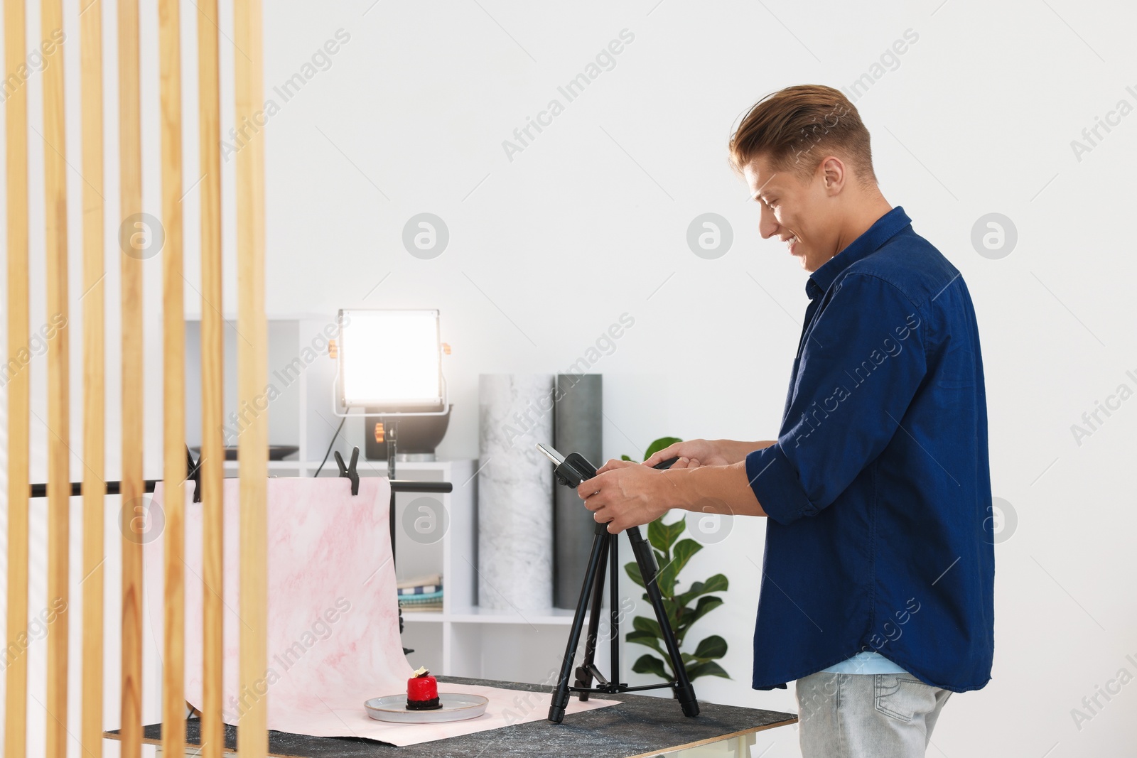 Photo of Man taking picture of tasty dessert in studio. Professional food photography