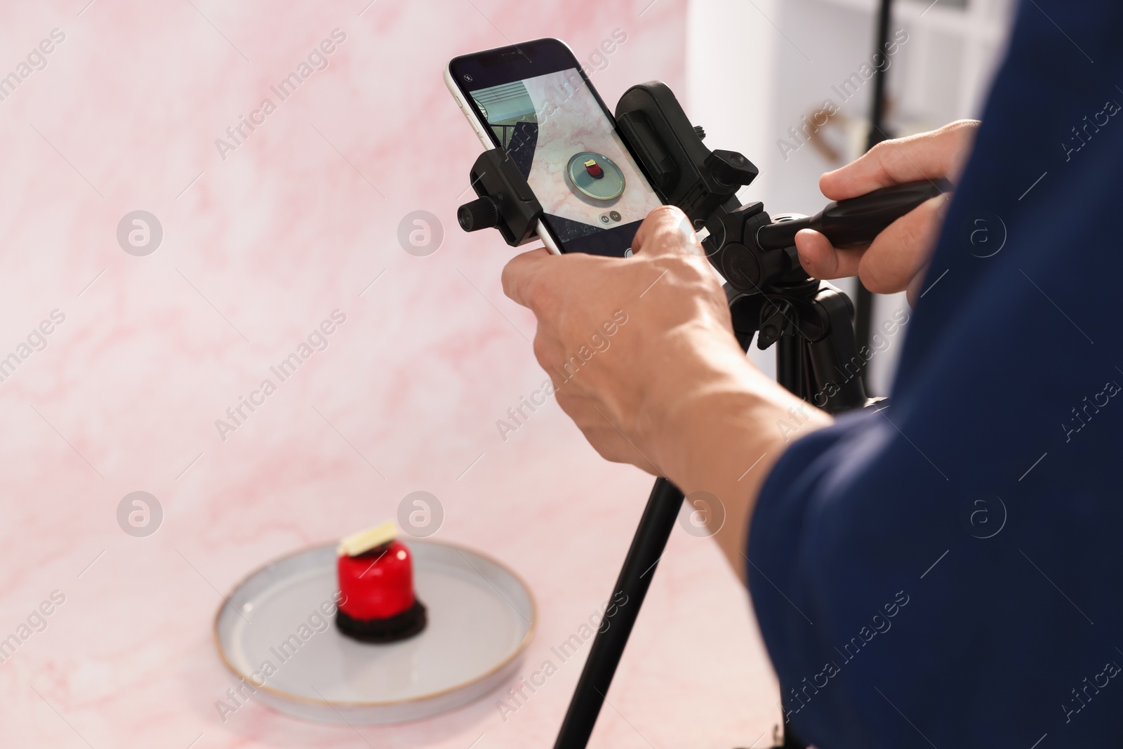 Photo of Man taking picture of tasty dessert in studio, selective focus. Professional food photography
