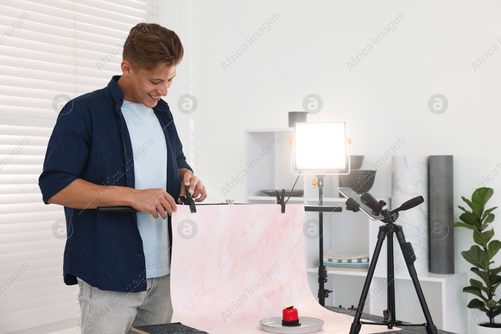 Photo of Man creating composition with tasty dessert for photoshoot at table in studio. Professional food photography