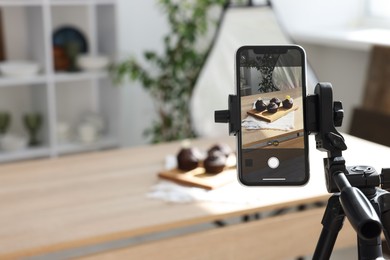 Photo of Shooting chocolate muffins with smartphone in studio, selective focus. Professional food photography