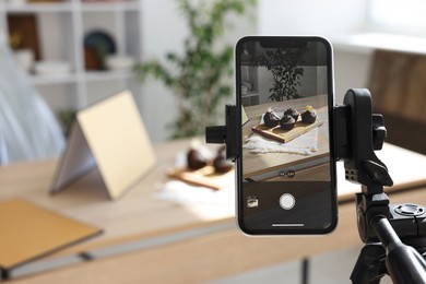 Photo of Shooting chocolate muffins with smartphone in studio, selective focus. Professional food photography