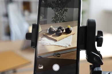 Photo of Shooting chocolate muffins with smartphone in studio, selective focus. Professional food photography