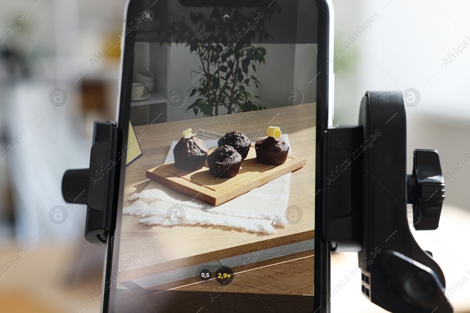Photo of Shooting chocolate muffins with smartphone in studio, selective focus. Professional food photography
