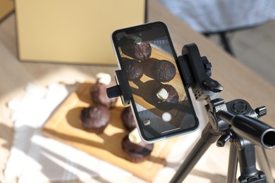 Photo of Shooting chocolate muffins with smartphone in studio, closeup. Professional food photography