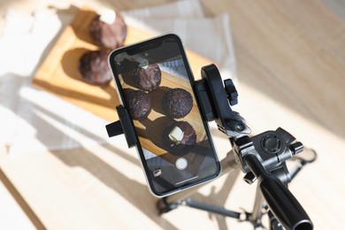 Photo of Shooting chocolate muffins with smartphone in studio, above view. Professional food photography