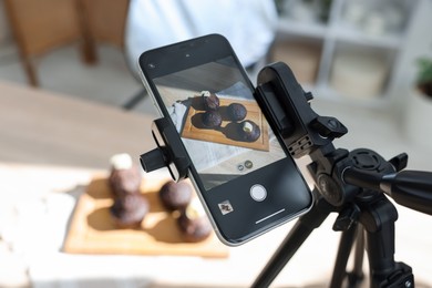 Photo of Shooting chocolate muffins with smartphone in studio, selective focus. Professional food photography