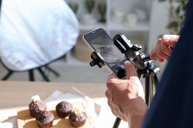 Photo of Man taking picture of chocolate muffins in studio, selective focus. Professional food photography