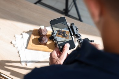 Photo of Man taking picture of chocolate muffins in studio, above view. Professional food photography