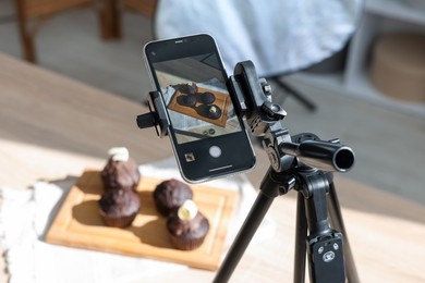 Photo of Shooting chocolate muffins with smartphone in studio, closeup. Professional food photography