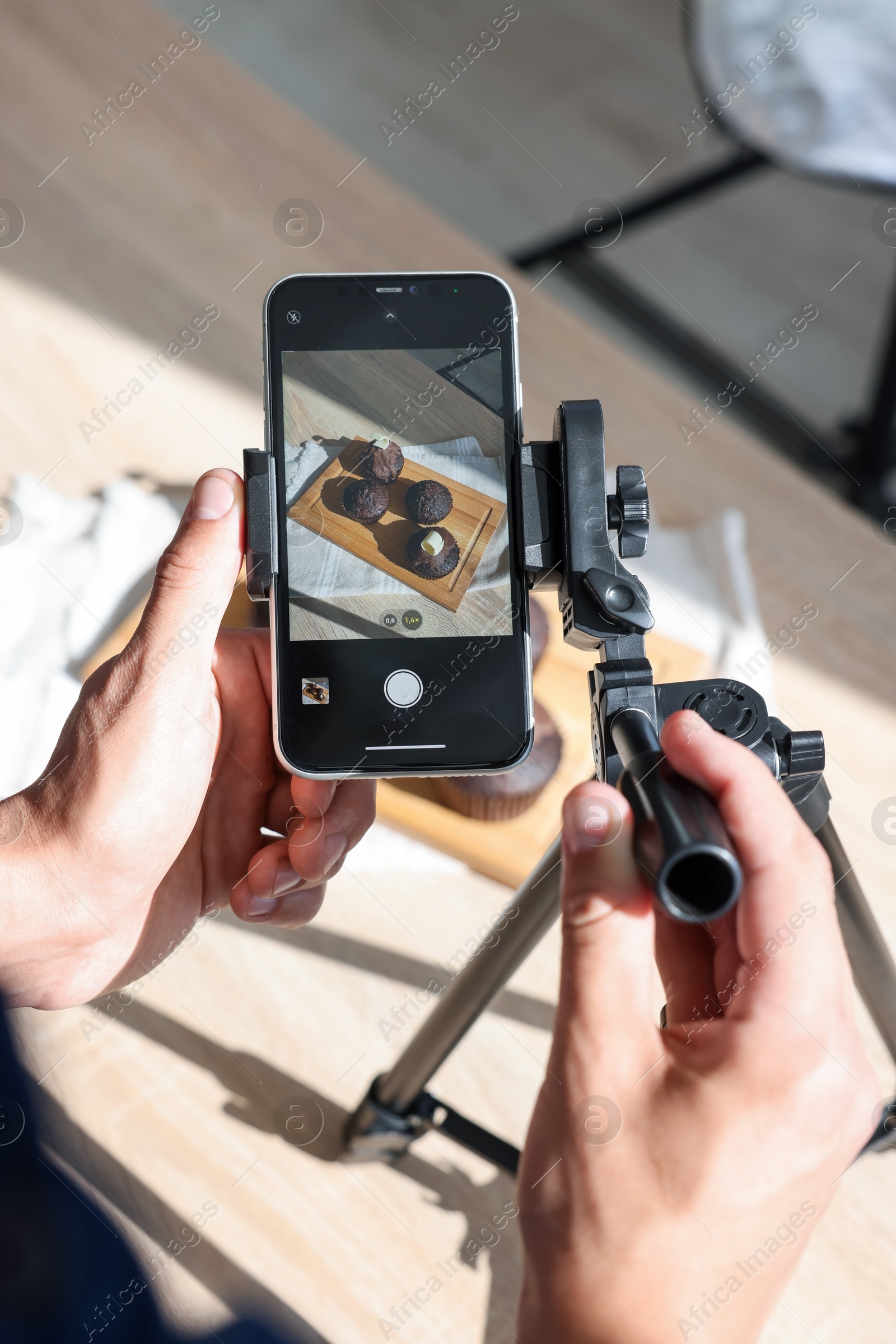Photo of Man taking picture of chocolate muffins in studio, above view. Professional food photography