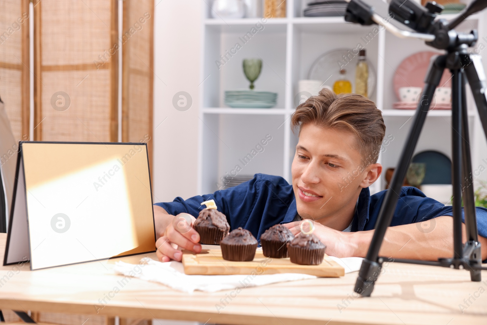 Photo of Man preparing chocolate muffins for photoshoot at table in studio. Professional food photography