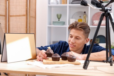 Photo of Man preparing chocolate muffins for photoshoot at table in studio. Professional food photography
