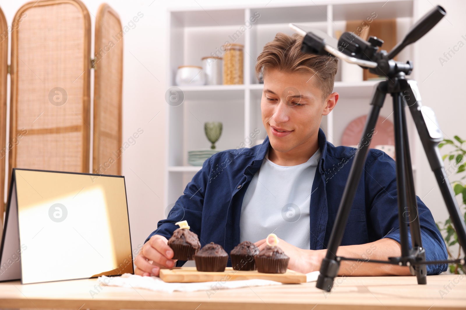 Photo of Man preparing chocolate muffins for photoshoot at table in studio. Professional food photography