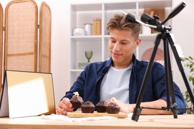 Photo of Man preparing chocolate muffins for photoshoot at table in studio. Professional food photography