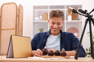 Photo of Man preparing chocolate muffins for photoshoot at table in studio. Professional food photography