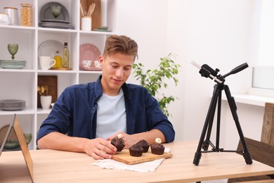 Photo of Man preparing chocolate muffins for photoshoot at table in studio. Professional food photography