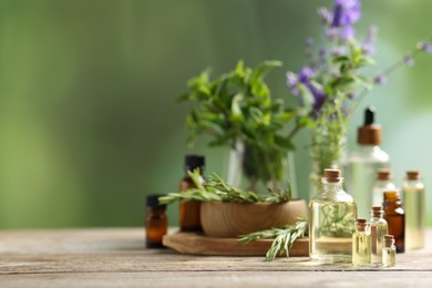 Photo of Bottles of essential oils and different herbs on wooden table outdoors, space for text