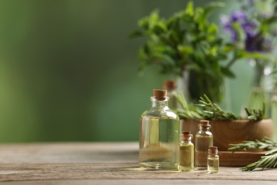 Photo of Bottles of essential oils and different herbs on wooden table outdoors, space for text