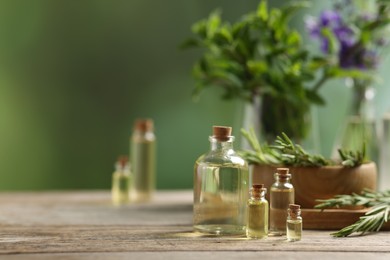 Photo of Bottles of essential oils and different herbs on wooden table outdoors, space for text