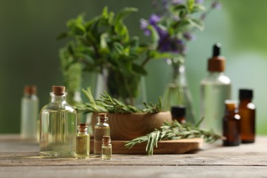 Photo of Bottles of essential oils and different herbs on wooden table outdoors