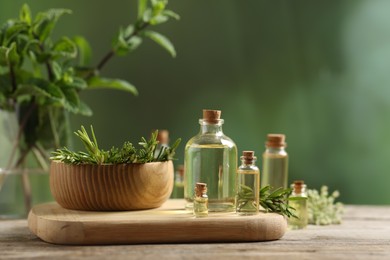 Photo of Bottles of essential oils and different herbs on wooden table outdoors