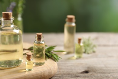 Photo of Bottles of essential oils and different herbs on wooden table outdoors, closeup. Space for text