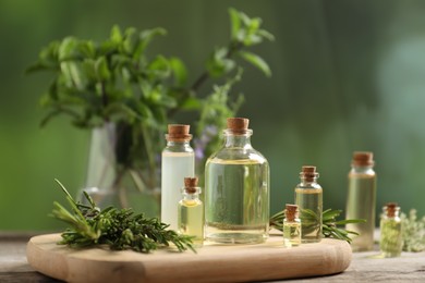Photo of Bottles of essential oils and different herbs on wooden table outdoors, closeup