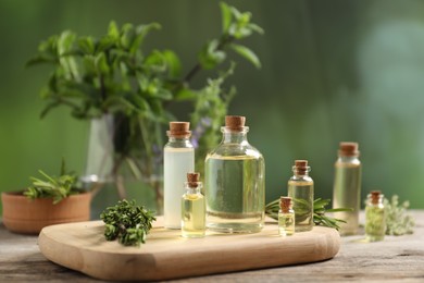 Photo of Bottles of essential oils and different herbs on wooden table outdoors, closeup