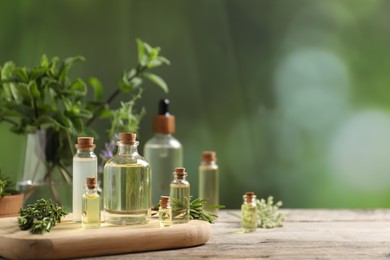 Photo of Bottles of essential oils and different herbs on wooden table outdoors, closeup. Space for text