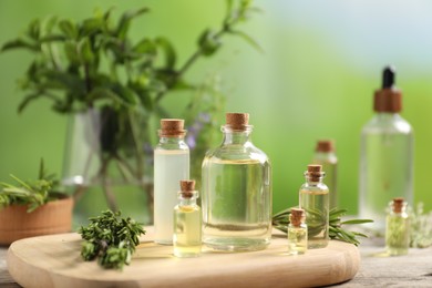 Photo of Bottles of essential oils and different herbs on wooden table outdoors, closeup