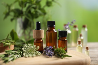 Photo of Bottles of essential oils and different herbs on table outdoors, closeup