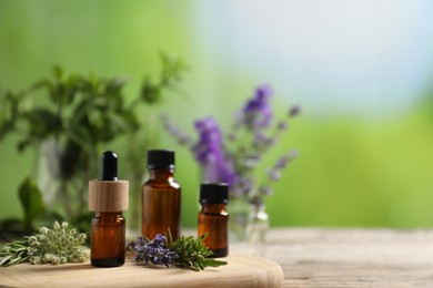 Photo of Bottles of essential oils and different herbs on table outdoors, closeup. Space for text