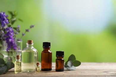 Photo of Bottles of essential oils and different plants on wooden table outdoors, closeup. Space for text