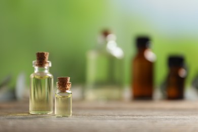 Photo of Bottles of essential oils on wooden table outdoors, closeup. Space for text