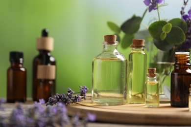 Photo of Bottles of essential oils and different plants on table outdoors, closeup