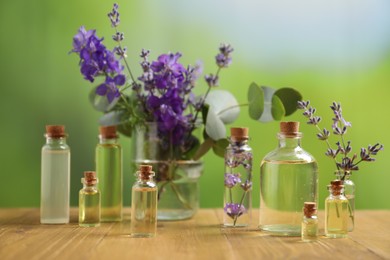 Photo of Bottles of essential oils and different plants on wooden table outdoors, closeup