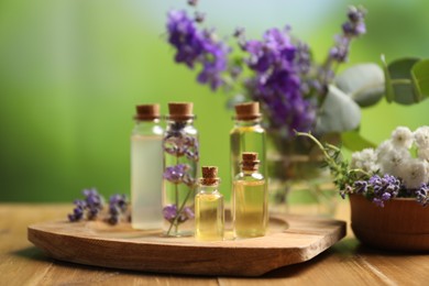 Photo of Bottles of essential oils and different plants on wooden table outdoors, closeup