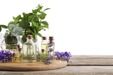 Photo of Bottles of essential oils and different plants on wooden table against white background