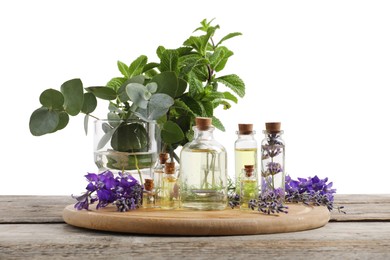 Photo of Bottles of essential oils and different plants on wooden table against white background