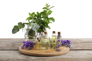 Photo of Bottles of essential oils and different plants on wooden table against white background
