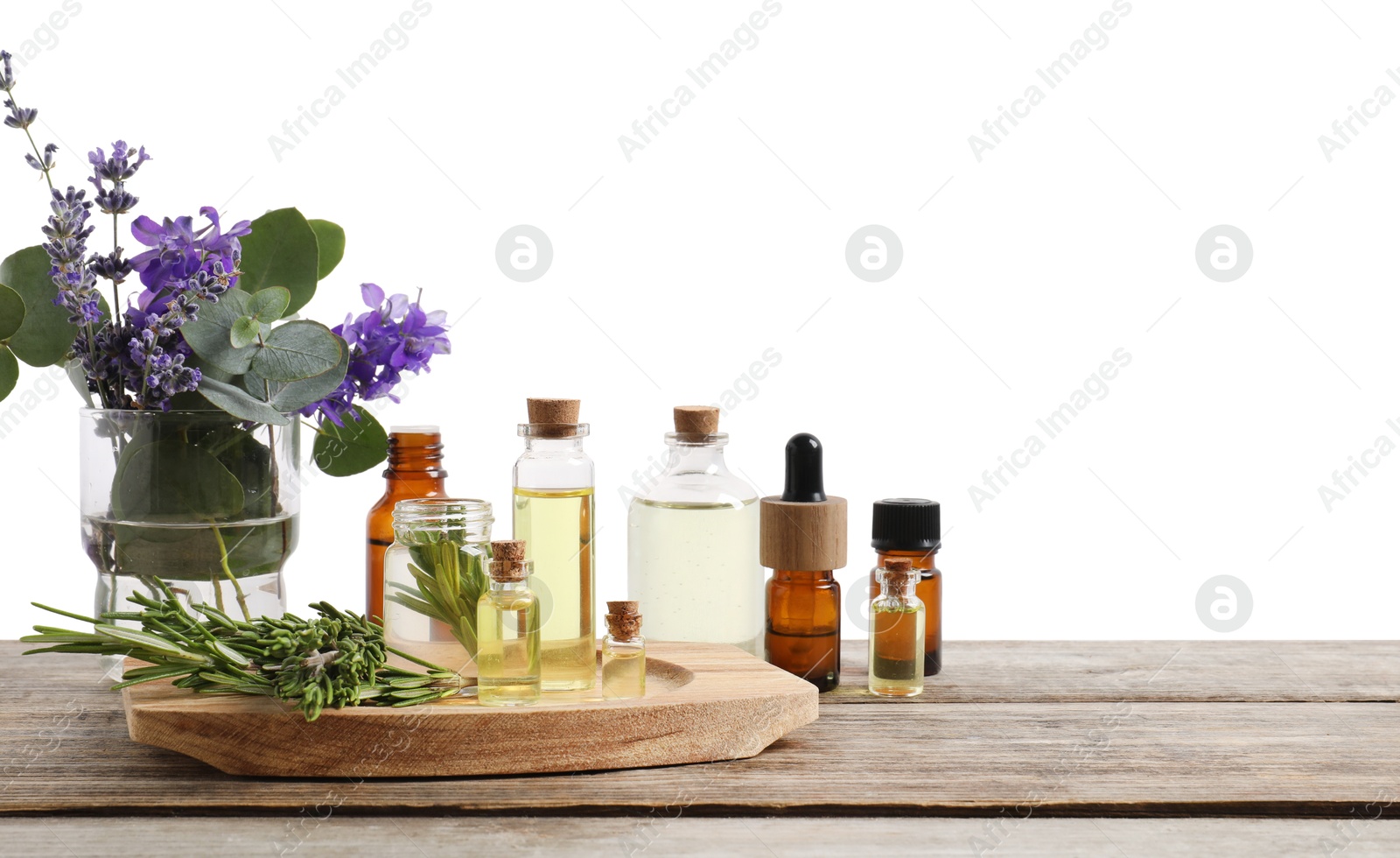 Photo of Bottles of essential oils and different plants on wooden table against white background