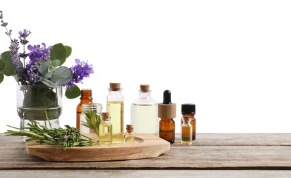 Photo of Bottles of essential oils and different plants on wooden table against white background