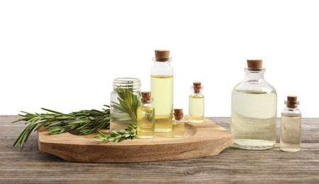 Photo of Bottles of essential oils and rosemary on wooden table against background