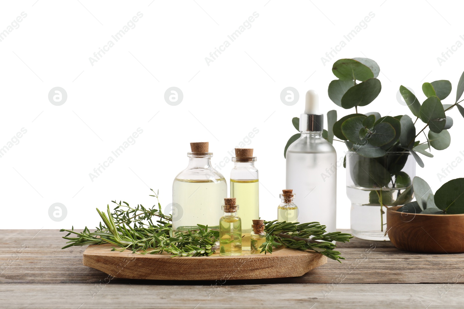 Photo of Bottles of essential oils, thyme, eucalyptus leaves and rosemary on wooden table against background